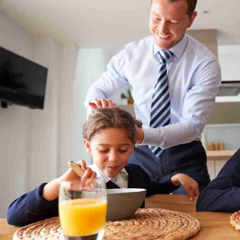 Businessman Father In Kitchen Brushing Hair And Helping Children With Breakfast Before School