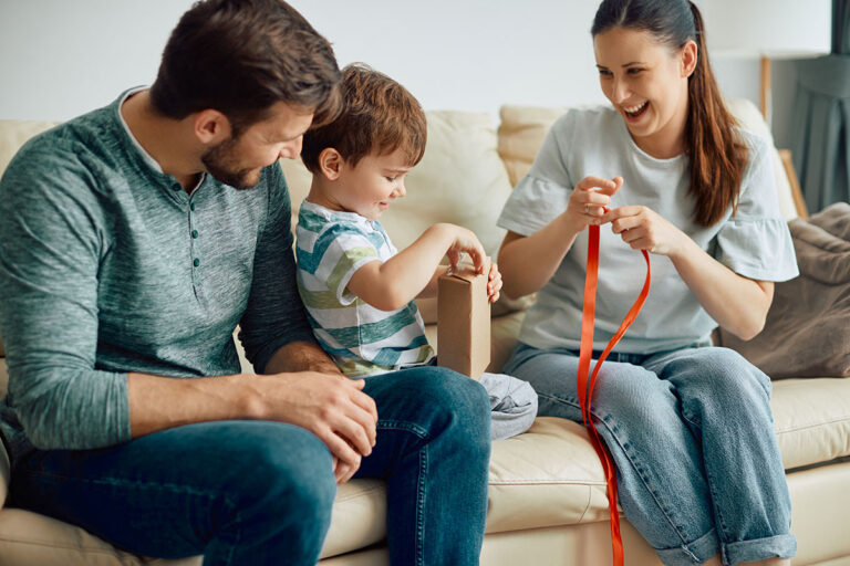 young-happy-family-opening-gift-box-together-at-ho-2024-12-13-18-17-56-utc